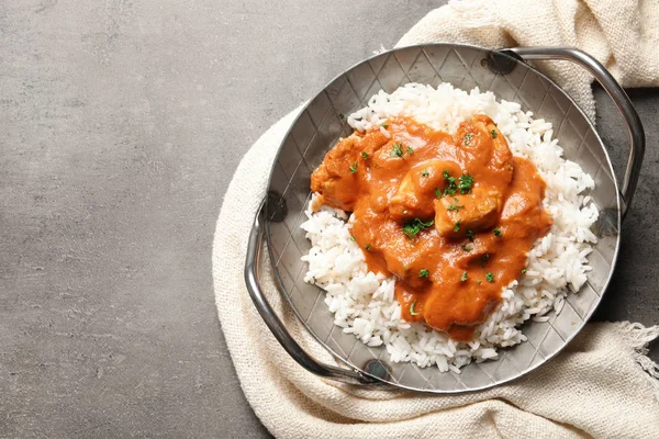 Delicious butter chicken with rice in dish and napkin on grey background, top view. Space for text