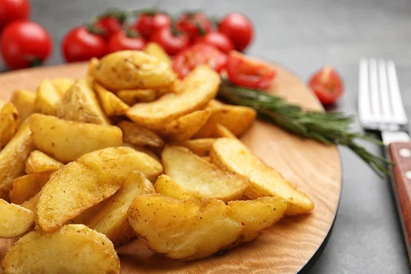 Prato com saborosas fatias de batata assadas na mesa, close-up — Fotografia de Stock