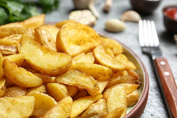 Piatto con gustosi cunei di patate al forno sul tavolo, primo piano — Foto Stock
