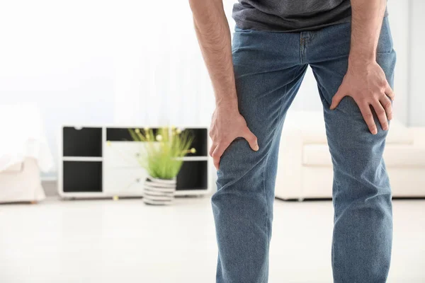 Young man suffering from leg pain indoors, closeup. Space for text — Stock Photo, Image