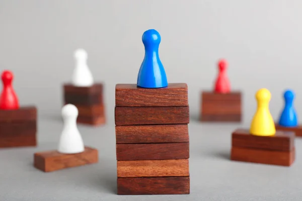 Juego de mesa en bloques de madera que dominan otras figuras sobre fondo gris. Concepto de victoria — Foto de Stock