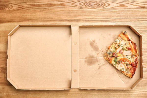 Caja de cartón con piezas de pizza sobre fondo de madera, vista superior — Foto de Stock