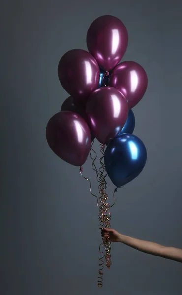 Kobieta trzyma kilka balonów na szarym tle, zbliżenie — Zdjęcie stockowe