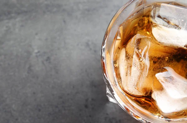 Glass of whiskey with ice cubes on grey background, top view. Space for text — Stock Photo, Image