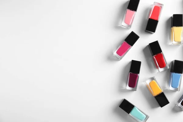 Bottles of bright nail polish on white background, top view — Stock Photo, Image