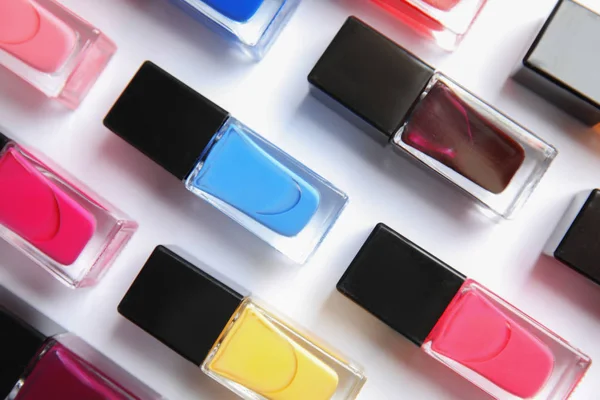 Bottles of bright nail polish on white background, top view — Stock Photo, Image