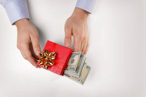 Homem segurando caixa de presente com notas de dólar no fundo branco, vista superior — Fotografia de Stock