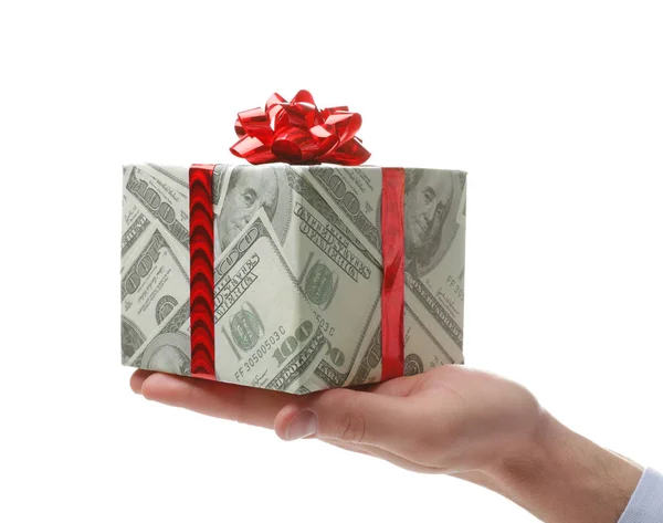 Hombre sosteniendo caja de regalo envuelta en papel decorativo con patrón de dólar sobre fondo blanco, primer plano — Foto de Stock