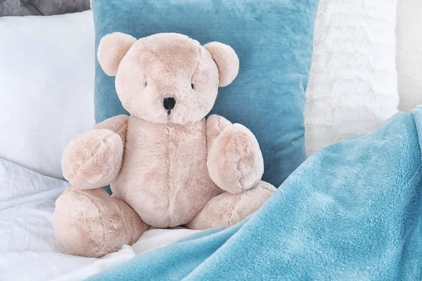 Niedlicher Teddybär sitzt drinnen im Bett. Raum für Text — Stockfoto