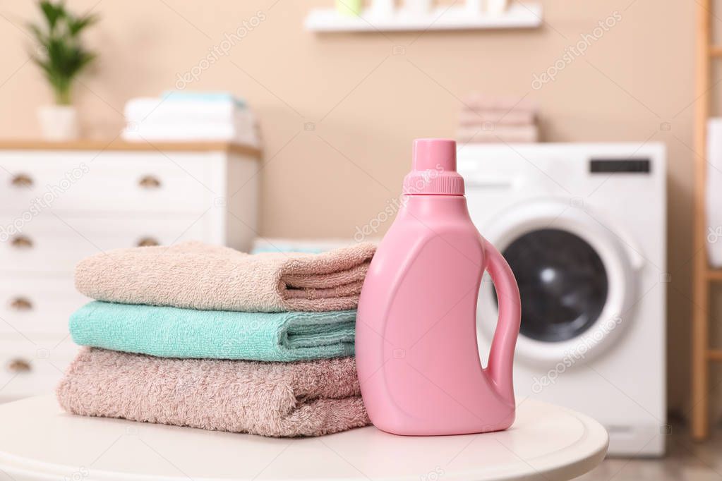 Stack of towels and detergent on table against blurred background