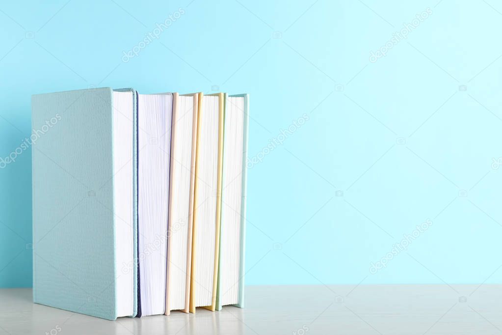Hardcover books on table against color background, space for text