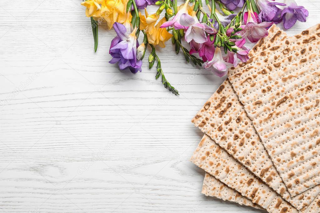Flat lay composition of matzo and flowers on wooden background, space for text. Passover (Pesach) Seder