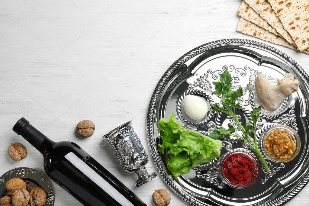 Flat lay composition with symbolic Passover (Pesach) items and meal on wooden background, space for text