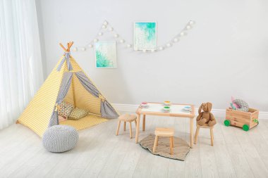 Cozy kids room interior with table, play tent and toys clipart