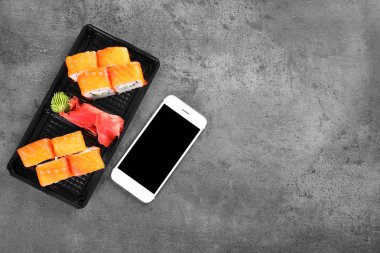 Lezzetli suşi rulo ve smartphone ile metin gri tablo, en iyi görünüm için yer. Food teslim
