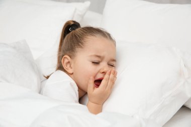 Güzel küçük kız yatakta. Yatmadan zamanlama