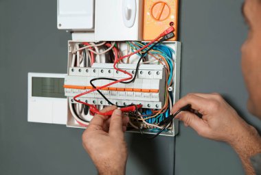 Elektrikçi ve testçi içeride voltajı kontrol ediyor, yakın plan.