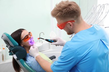 Profesyonel diş hekimi modern klinik hasta ile çalışma. Diş beyazlatma