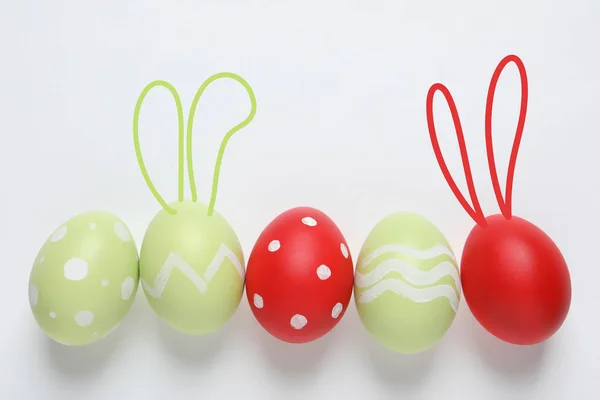 Set di uova colorate con orecchie di coniglio pasquali su sfondo chiaro, vista dall'alto — Foto Stock