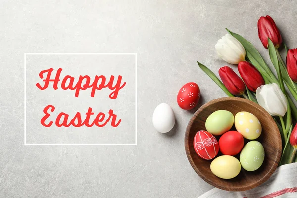 Flat lay composition of painted eggs and text Happy Easter on light background