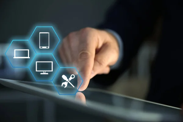 Geschäftsmann mit digitalem Tablet und verschiedenen Symbolen auf verschwommenem Hintergrund, Nahaufnahme. technische Unterstützung — Stockfoto