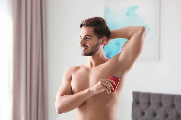 Joven guapo aplicando desodorante en la habitación — Foto de Stock