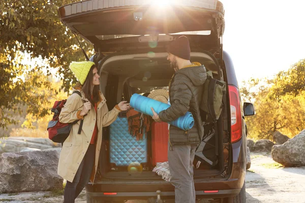 Young couple with camping equipment near car trunk outdoors — Stock Photo, Image