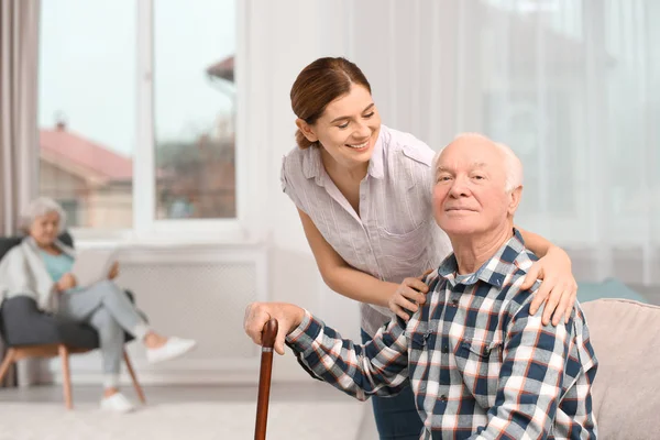 Ένας ηλικιωμένος άνδρας με γυναίκα φροντιστή στο σπίτι. Χώρο για το κείμενο — Φωτογραφία Αρχείου