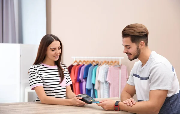 Hombre usando terminal para pago con tarjeta de crédito en tienda — Foto de Stock