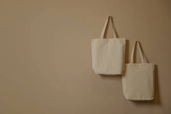 Eco tote bags hanging on color wall. Space for design — Stock Photo, Image