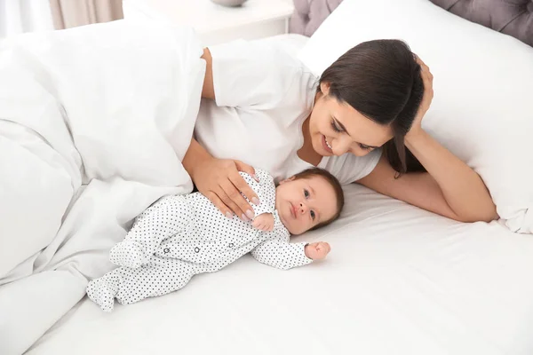 Mujer feliz con su lindo bebé en la cama — Foto de Stock