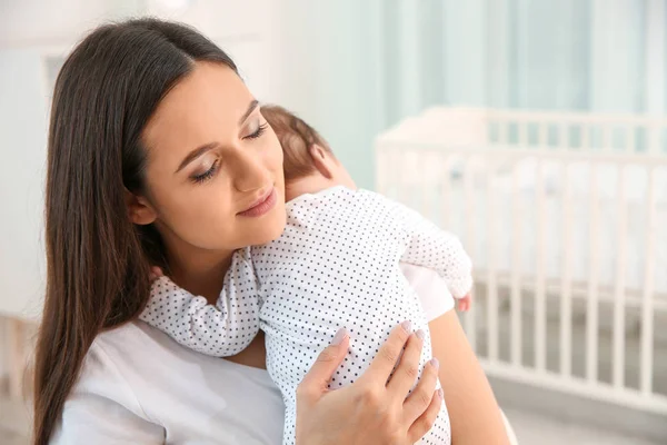Vrouw met haar baby in lichte kinderkamer. Ruimte voor tekst — Stockfoto
