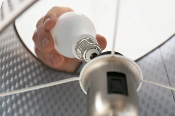 Man changing light bulb in lamp, closeup. Low angle view — Stock Photo, Image