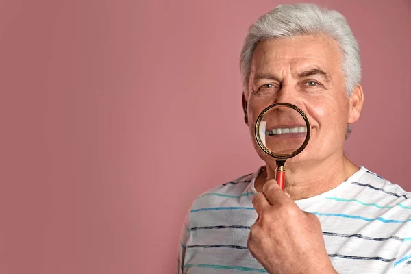 Mature man with healthy teeth and magnifier on color background. Space for text — Stock Photo, Image