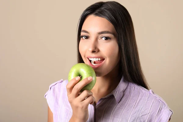 Mujer joven con dientes sanos y manzana sobre fondo de color — Foto de Stock