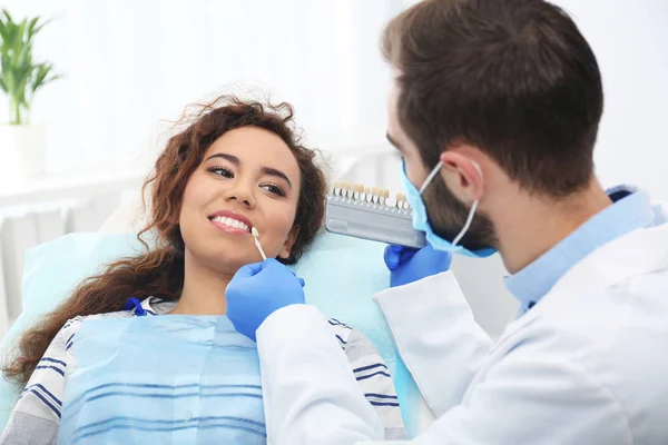 Zubař odpovídající barvy zubů pacienta s paletou v úřadu — Stock fotografie