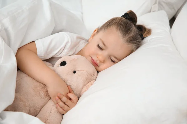 美丽的小女孩睡在床上的玩具。睡觉时间时间表 — 图库照片