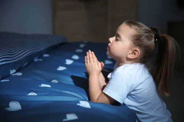 Little girl saying bedtime prayer near bed in room at night — Stock Photo, Image