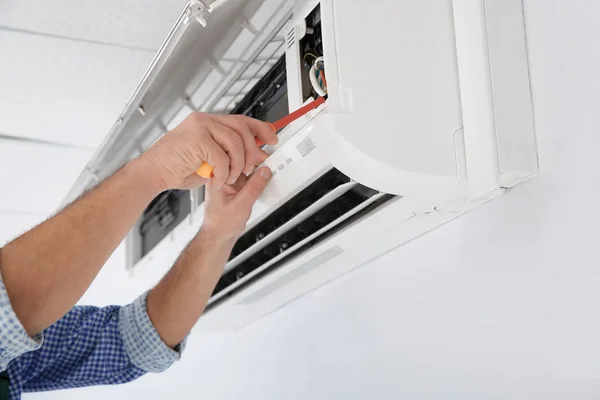 Elektriker mit Schraubenzieher repariert Klimaanlage drinnen, Nahaufnahme — Stockfoto