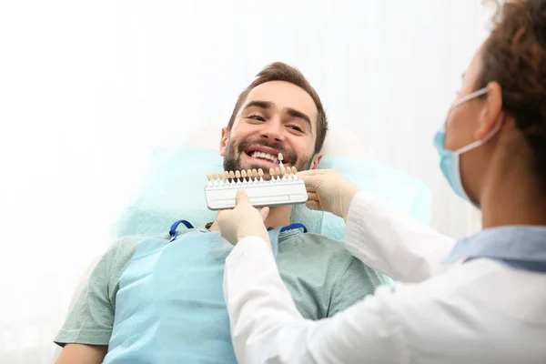 Zahnarzt passt Zahnfarbe des jungen Mannes mit Palette im Büro an — Stockfoto