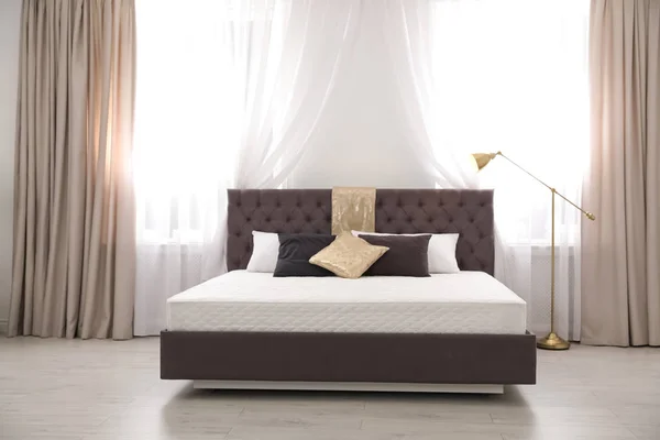 Комфортне ліжко з новим матрацом біля вікна в кімнаті. Здоровий сон — стокове фото