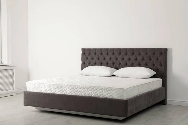 Комфортабельная кровать с новой матрешкой у стены в комнате. Здоровый сон — стоковое фото