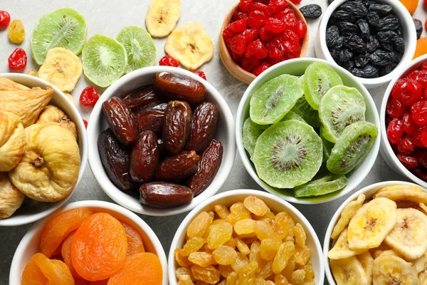 Bowls with different dried fruits on grey background, flat lay. Healthy food — Stock Photo, Image