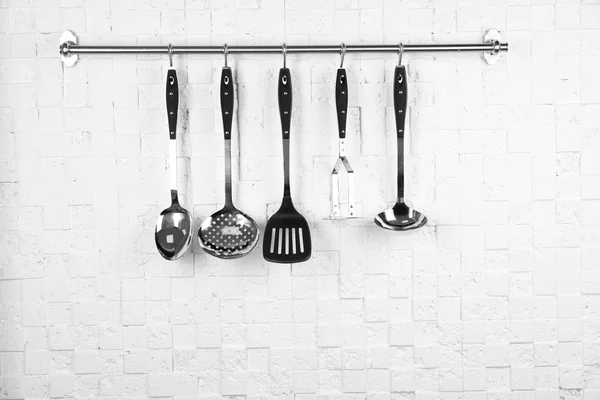 Cremalheira com utensílios de cozinha limpos na parede branca — Fotografia de Stock