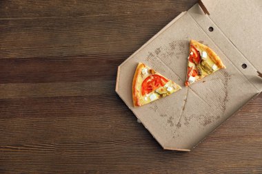 Karton kutu ahşap arka plan, üstten görünüm lezzetli pizza dilimleri ile. Metin için yer