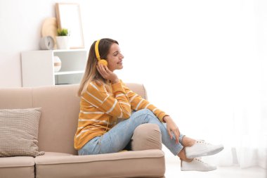 Genç kadın evde kanepe üzerinde müzik keyfi kulaklık