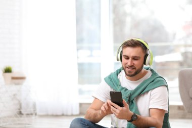Oturma odasında müzik keyfi hareket eden aygıt ve kulaklık ile genç adam