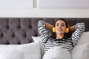 Genç kızla yatakta müzik keyfi kulaklık