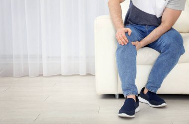 Genç adam bacak ağrısı kapalı, closeup acı. Metin için yer