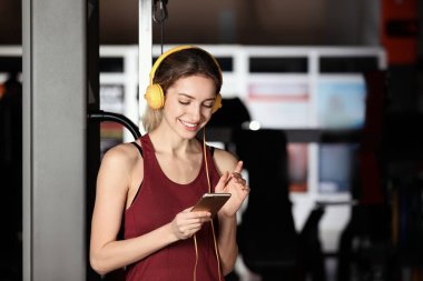 Genç kadın kulaklıklarla müzik üstünde hareket eden aygıt vasıl jimnastik salonu